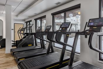 A gym with treadmills and a view of the street outside.